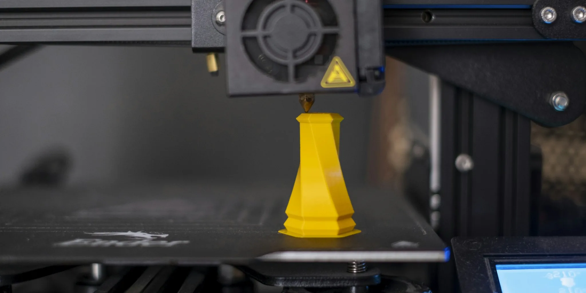 3D printer with printed model in foreground during operation