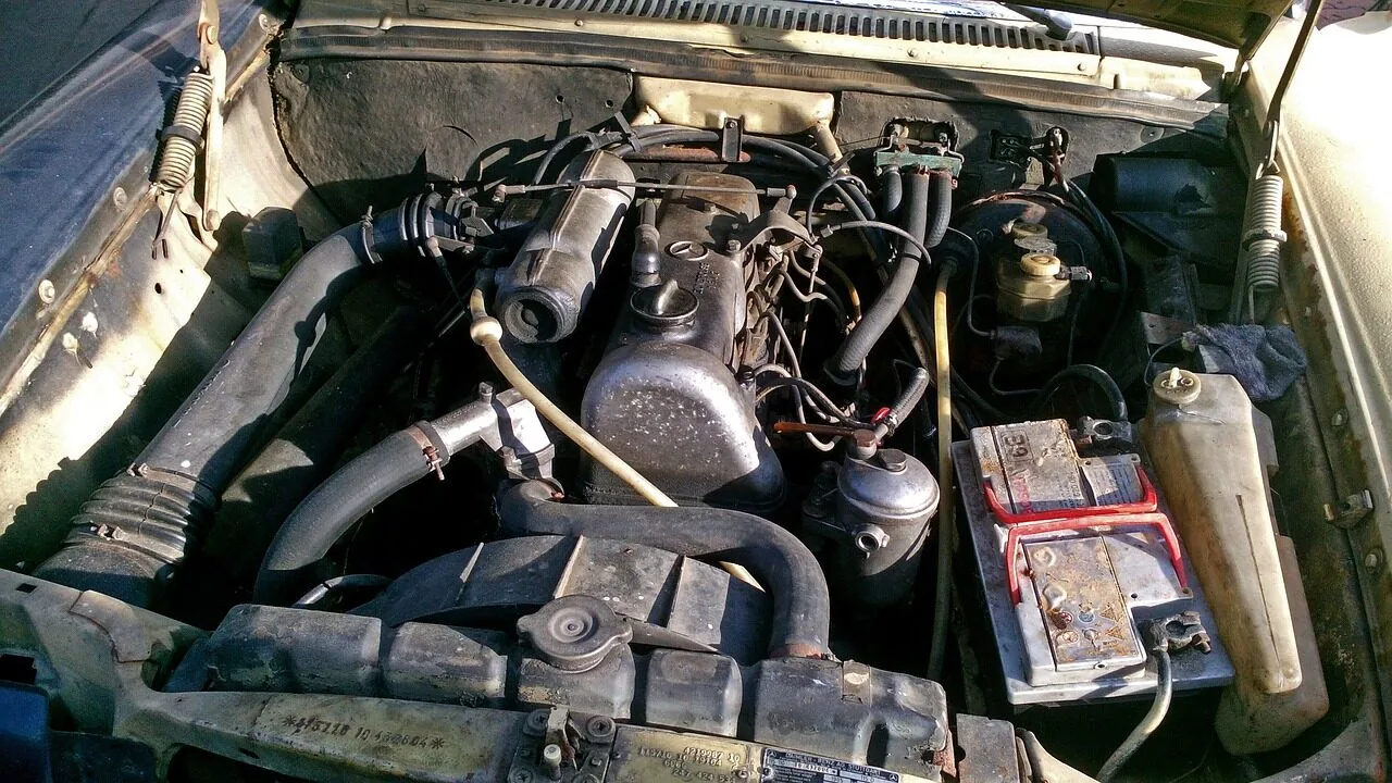 Car battery installed in vehicle engine compartment showing terminals and connections