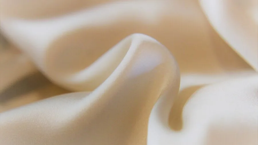 Close-up of soft white cotton bed sheets showing natural fabric texture and weave detail