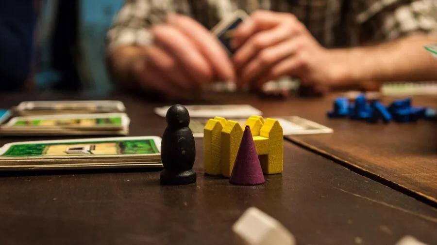 Friends gathered around a table enjoying a board game with themed components and creative artwork