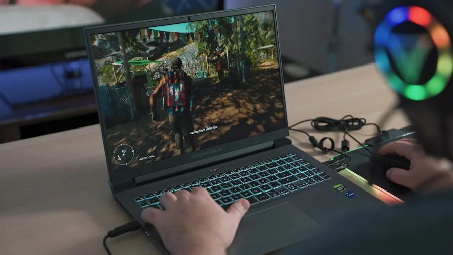 Gamer streaming gameplay on laptop with professional microphone and RGB lighting in home studio