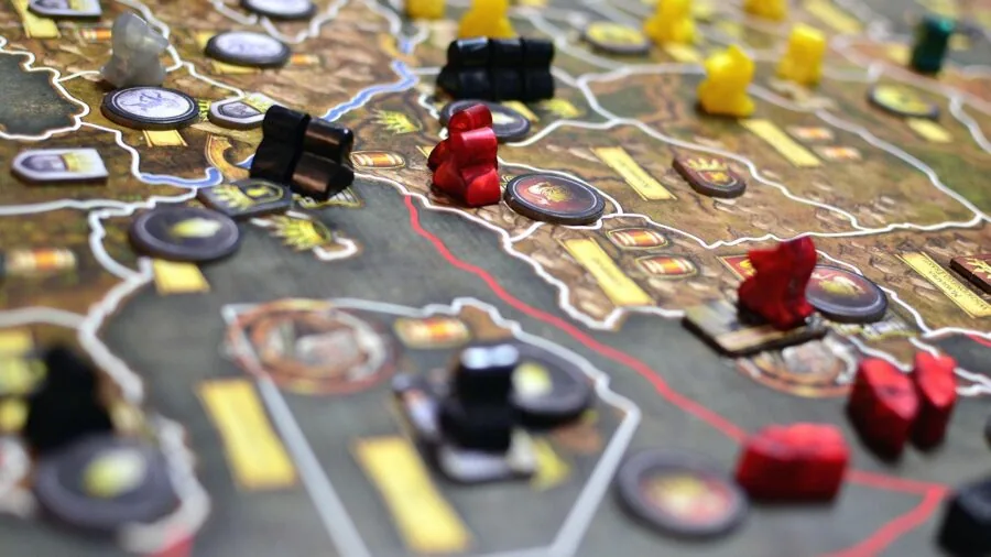 Group of friends gathered around a table playing a strategic board game together indoors