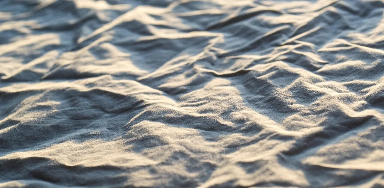 High-quality bed sheets draped on bed in natural light