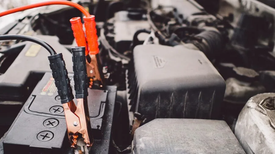 Mechanic inspecting vehicle battery under open hood in professional garage setting