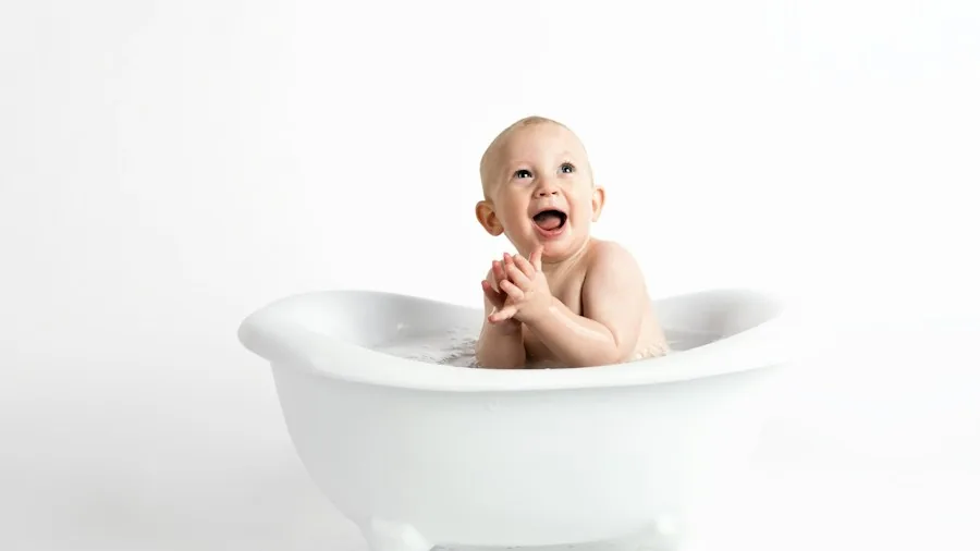 Parent bathing toddler in bathroom, showing different bathing stages and child development growth