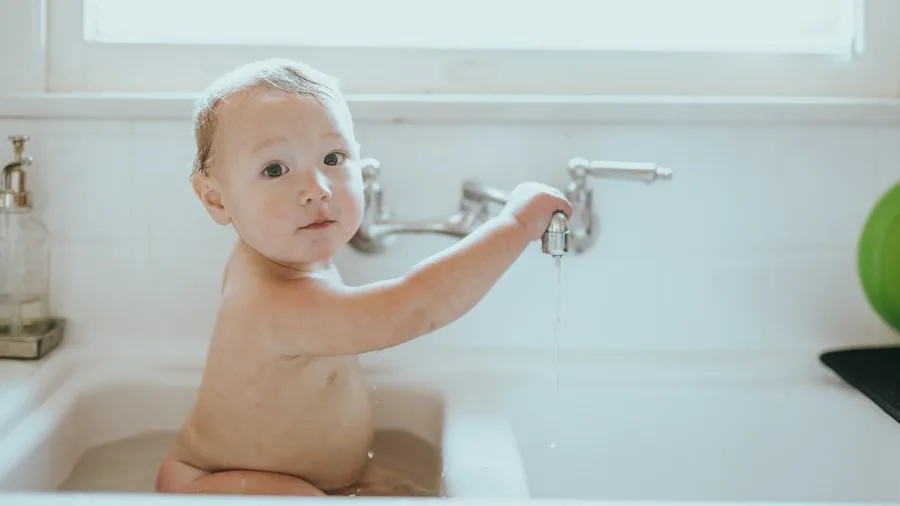 Parent gently bathing baby in warm water with careful attention to safety and comfort