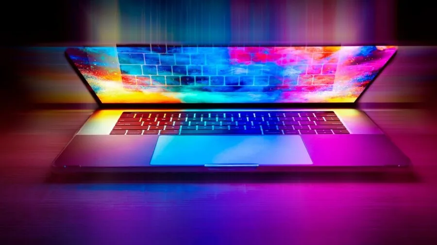 Person immersed in gaming on laptop with vibrant screen graphics and ambient lighting