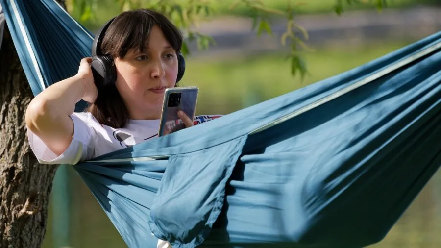 Person lounging in a hammock strung between trees in a peaceful outdoor setting