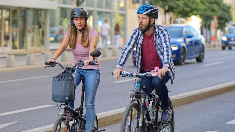 Person riding bicycle on city street with pedestrians and traffic in background