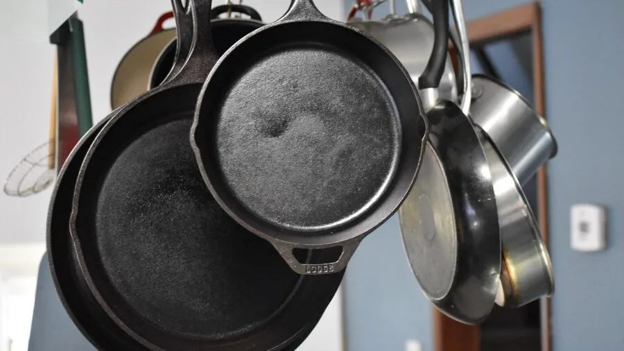 Person seasoning and maintaining a traditional cast iron skillet in a home kitchen environment