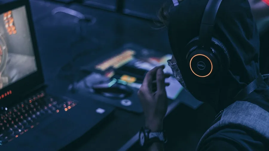 Person using gaming laptop with visible cooling vents during intense gaming session