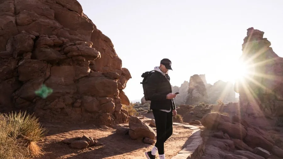 Person wearing sturdy backpack on mountain trail during outdoor hiking expedition