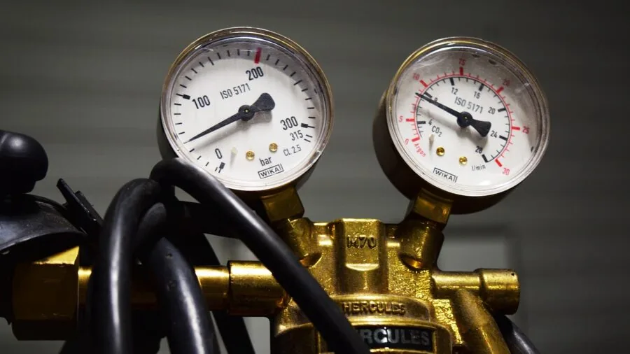 Professional mechanic checking air compressor pressure gauge while working on pneumatic tools in workshop